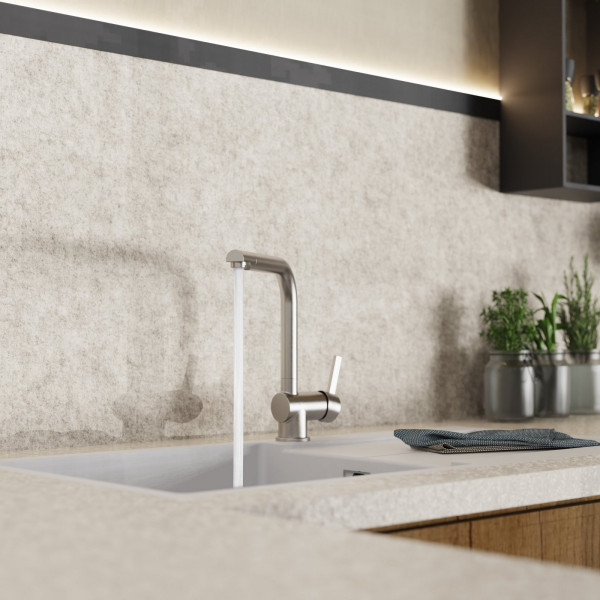 Edelstahl-Küchenarmatur mit laufendem Wasserstrahl über weißem Spülbecken.