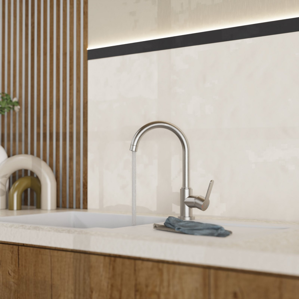 Wasserhahn aus Edelstahl mit fließendem Wasser an Spüle mit heller Arbeitsplatte.