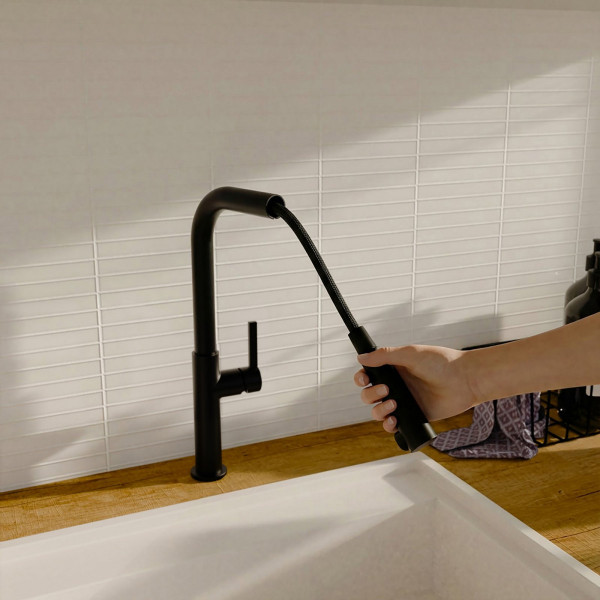 Hand zieht ausziehbaren schwarzen Küchenwasserhahn über weißem Waschbecken heraus.