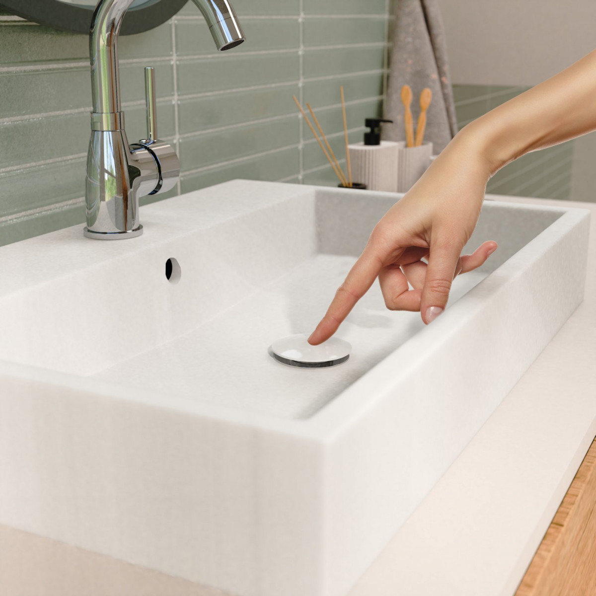 Hand drückt auf den Abflussstopfen eines weißen Waschbeckens mit Chromarmatur.