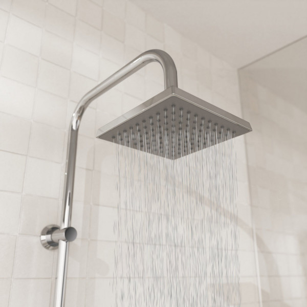 Quadratische Edelstahl-Regendusche mit Wasserstrahl vor heller Fliesenwand