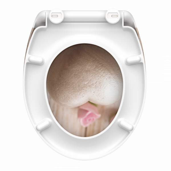 Weißer WC-Sitz mit Motiv aus Steinherz und rosa Rose auf Holzuntergrund.