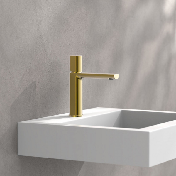 Goldfarbene Einhebelarmatur an weißem, wandmontiertem Waschbecken vor grauer Wand.