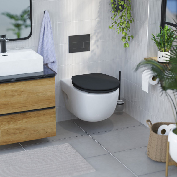 Wandhängende weiße Toilette mit schwarzem Sitz im modernen Badezimmer mit Pflanzen.