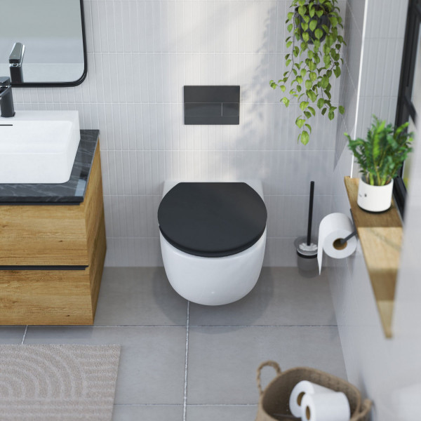 Wandhängende weiße Toilette mit schwarzem WC-Sitz neben Holzwaschtisch und Pflanzen.
