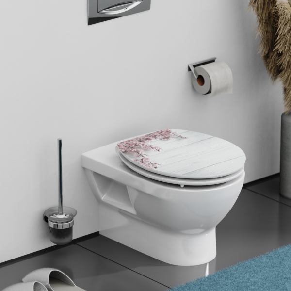 Wandmontierte weiße Toilette mit geschlossenem WC-Sitz in Holzoptik und Blütenmotiv.
