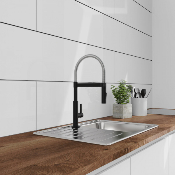 Edelstahlspüle mit hohem schwarzen Wasserhahn auf Holzarbeitsplatte in weißer Küche.
