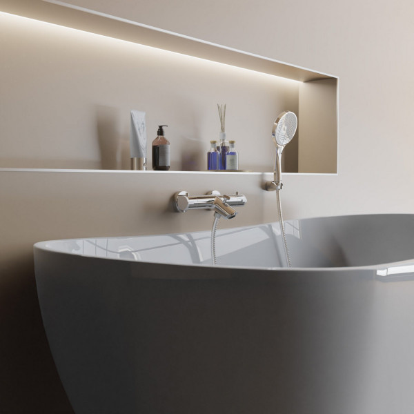 Wandarmatur in grauer Badewanne mit Duschbrause und Ablage mit Pflegeprodukten.