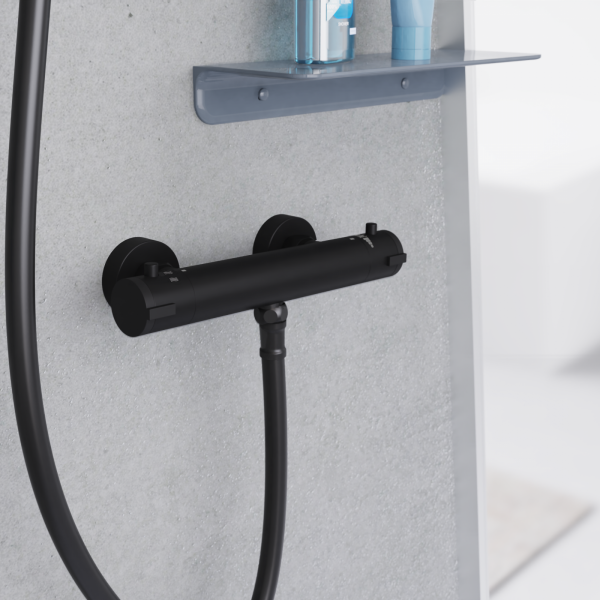 Schwarze Duscharmatur mit zwei Drehgriffen und angeschlossenem Duschschlauch an grauer Wand.