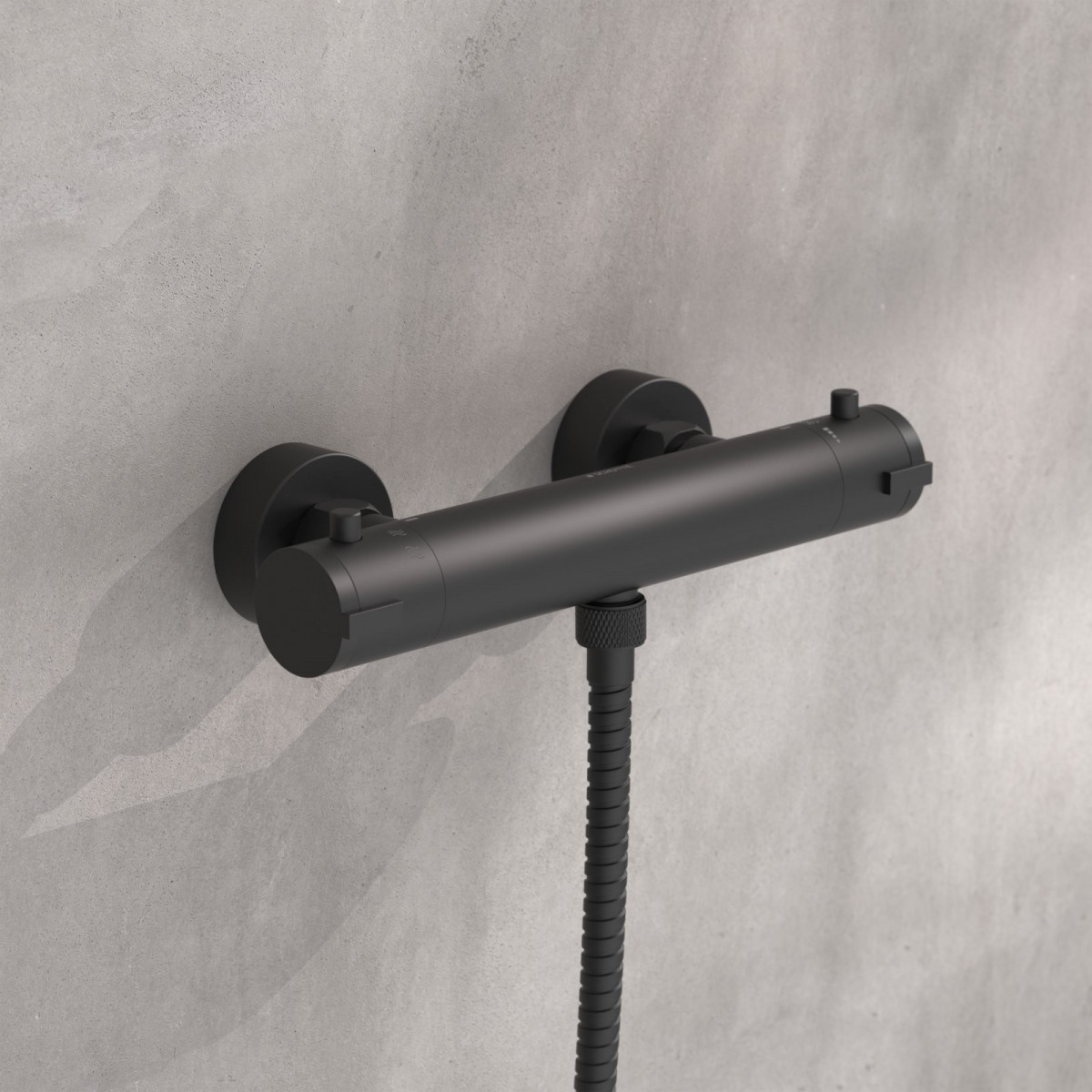 Schwarze Duscharmatur mit zwei Drehgriffen und angeschlossenem Duschschlauch an grauer Wand.