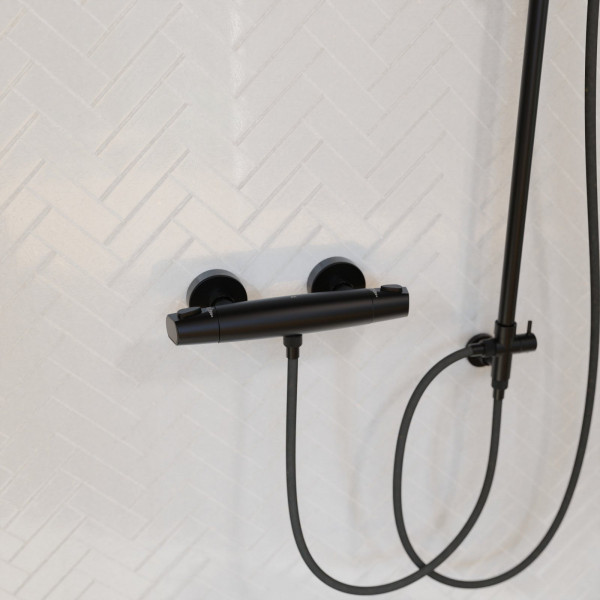 Schwarze Duscharmatur mit Schlauch und Halterung vor heller Wand