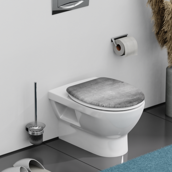 Wandhängende weiße Toilette mit geschlossenem grauen Toilettensitz und WC-Bürste daneben.